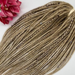 May include: A set of blonde synthetic dreadlocks with brown stitching and silver beads. The dreadlocks are arranged in a loose bundle.