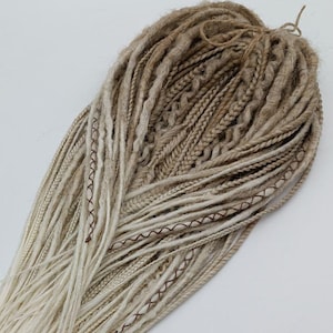 May include: A set of synthetic dreadlocks in two shades of brown, with the top section a darker brown and the bottom section a lighter brown. The dreadlocks are tied together with a brown string.