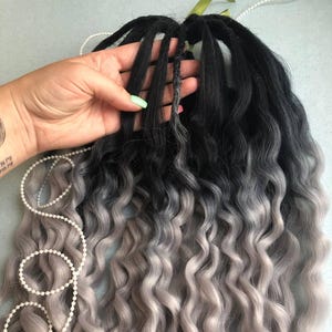 May include: A set of black and silver ombre curly synthetic dreadlocks. The dreadlocks are about 24 inches long and have a wavy texture.