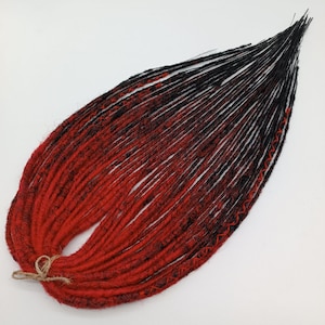 May include: A bundle of black and red ombre synthetic dreadlocks. The dreadlocks are made of kanekalon hair and are approximately 50 cm long.