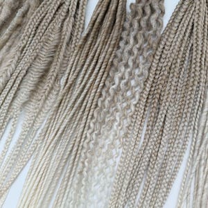 May include: A collection of various blonde synthetic hair extensions in different textures, including straight, wavy, and curly. The extensions are arranged in a fan shape, showcasing the different styles.