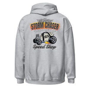 Può includere: Una felpa con cappuccio grigio chiaro con una grafica sul retro. Il design include il testo OLD SCHOOL STORM CHASER, SAME DAY SERVICE GUARANTEED e SPEED SHOP, con un'illustrazione di un veicolo hot rod con l'etichetta DRAG BAG.