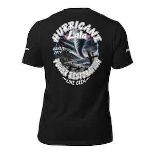 Può includere: Una t-shirt nera a maniche corte con una grafica sul retro. Il disegno mostra un tornado sopra un paesaggio costiero con il testo Hurricane Lala, Hawaii 2026, Power Restoration e Line Crew. Sulle maniche è presente del testo piccolo.
