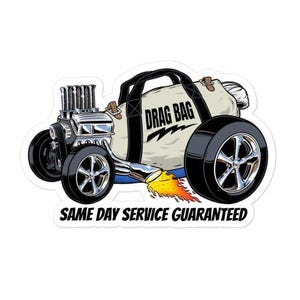 Könnte beinhalten: Ein Aufkleber mit einem Cartoon-Hot Rod mit einer beigen Reisetasche mit der Aufschrift "DRAG BAG". Das Auto hat Chromräder und Motorteile, mit Flammen, die aus dem Auspuff austreten. Der Text "SAME DAY SERVICE GUARANTEED" steht unten.