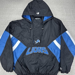 May include: Black, blue, and white Detroit Lions Starter jacket with a hood. The jacket features the Lions logo and the word "LIONS" in blue and white. The jacket has a quarter-zip closure and a Starter logo on the hood.