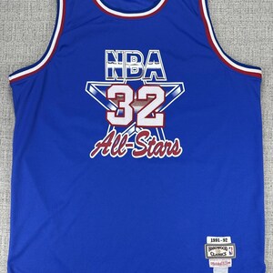 May include: A blue NBA All-Stars basketball jersey with the number 32 in white and red. The jersey has a white and red trim around the neck and armholes. The text "NBA All-Stars" is in white script. A tag on the bottom right corner reads "1991-92 Hardwood Classics".