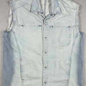 May include: A light blue denim vest with a button-up front and a single chest pocket. The vest has a frayed edge on the armholes.