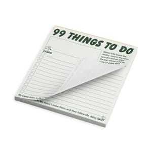May include: A white notepad titled 99 THINGS TO DO in dark green text. It features a task list with checkboxes, lines for writing, and Bible verses from Luke 15:4 and John 10:27. The top page is partially curled, revealing the lined pages underneath.