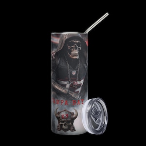 Op de afbeelding: Een roestvrijstalen beker met een ontwerp van een zeisdrager in een voetbaluniform. De beker heeft een zilveren rietje en een wit deksel. De woorden "TAMPA BAY" staan op de beker gedrukt. Het ontwerp bevat een schedel met een helm.