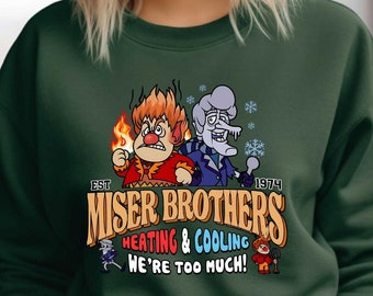 Può includere: Felpa verde scuro con grafica dei Miser Brothers, personaggi di un film d'animazione del 1974. Il design include il testo "Miser Brothers Heating & Cooling" e "We're Too Much!" con personaggi che rappresentano caldo e freddo.