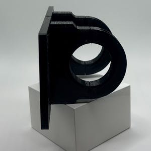 May include: A black plastic wall mount with two circular openings for mounting a camera or other device.