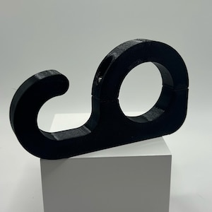 May include: Black plastic hook with a circular loop on one end. The hook is designed to hang items on a wall or other surface.
