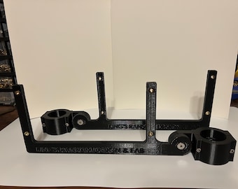 May include: Two black 3D printed brackets with adjustable swivel joints and the text "King's Ransom Design & Fab" printed on the bottom.