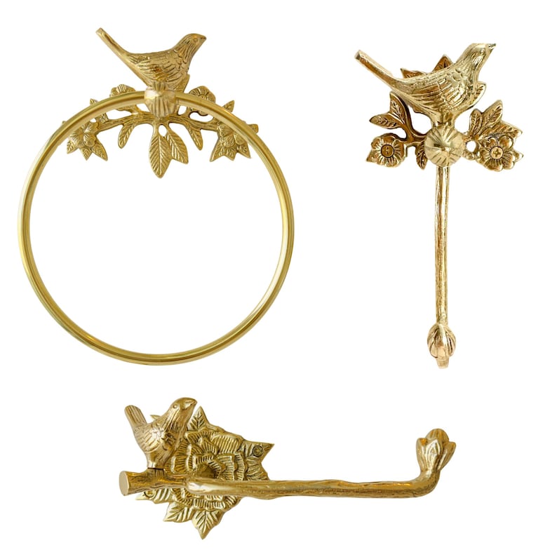 May include: A set of three brass bathroom fixtures. The set includes a towel ring, a hook, and a toilet paper holder. Each piece features a bird perched on a branch with leaves and flowers.