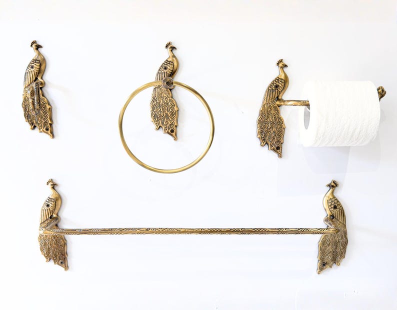 May include: A set of brass bathroom fixtures featuring peacock designs. The set includes a towel bar, a toilet paper holder, a towel ring, and two wall hooks, all with intricate peacock detailing. The fixtures are mounted on a white wall.