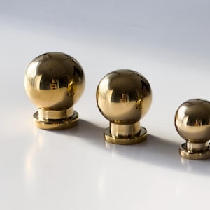 Peut inclure: Trois boutons en laiton poli de tailles différentes. Les boutons sont ronds et ont une finition lisse et brillante.