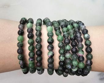 May include: A bracelet made of multiple strands of green and black gemstone beads. The beads are round and have a speckled appearance.