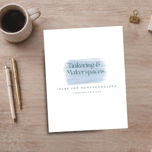 May include: A white sheet of paper with the text "Tinkering & Makerspaces" in blue and green, with the text "IDEAS FOR HOMESCHOOLERS" and "THEPAPERCABIN.COM" below. A cup of coffee and two pens are on the left, and a gold paper clip is on the right.