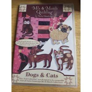 May include: A DVD case titled Mix & Match Quilting by Anita Goodesign featuring Dogs & Cats. The cover displays embroidered illustrations of a black cat, a tan pug, a brown dachshund, and a spotted cat against a pink and black quilted background.