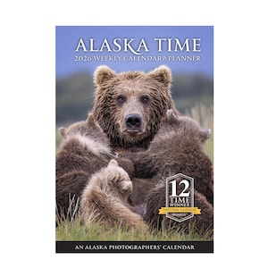 May include: A 2026 weekly calendar and planner featuring a brown bear with three cubs. The cover has the text "ALASKA TIME" and "AN ALASKA PHOTOGRAPHERS' CALENDAR". The calendar is a 12 Time Winner of the National Calendar Awards.