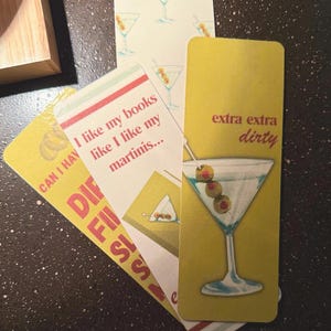 May include: Three yellow and white bookmark cards with a martini glass design. The text on the cards reads "Can I have", "I like my books like I like my martinis...", and "extra extra dirty".