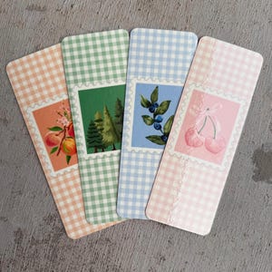 May include: Four gingham bookmark designs with different illustrations. The bookmarks are in pink, blue, green, and orange gingham patterns. The illustrations include peaches, blueberries, a forest, and cherries.