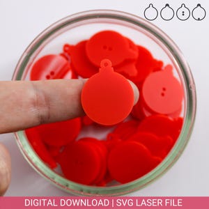 Pode incluir: Um close-up de um ornamento de Natal redondo vermelho com um laço no topo. O ornamento está sendo segurado por um dedo. Há muitos outros ornamentos vermelhos no fundo.