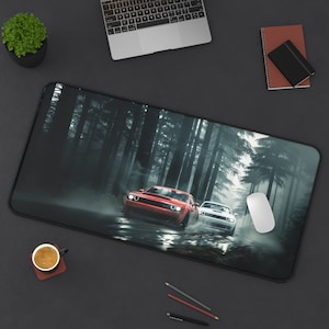May include: A black rectangular mousepad featuring a red and white sports car racing through a misty forest. The cars are the focal point, with the forest in the background. A white mouse and other office supplies are also visible.