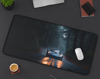 Peut inclure: Un tapis de souris noir avec une scène de forêt sombre et une voiture de sport bleue roulant sur une route. Les phares de la voiture sont allumés et la route est mouillée.