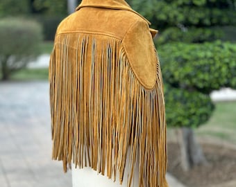 May include: A brown suede jacket with fringe detailing. The jacket has a collar and long sleeves. The fringe is on the bottom of the jacket and the sleeves.