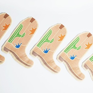 May include: Five brown cowboy boot shaped paper party decorations with green cactus and orange star designs.