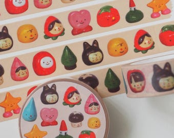 May include: Decorative washi tape featuring a variety of colorful, cartoonish clay figures. The tape roll and strips display images of smiling characters, including a mushroom, a bunny, a tomato, and a star. The text "clay natamori" is printed on the tape roll.