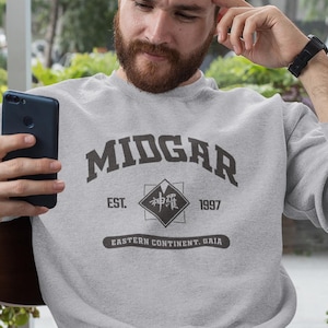 May include: A gray sweatshirt with the text "MIDGAR EST. 1997 EASTERN CONTINENT. GAIA" and a black square with Japanese characters in the center.
