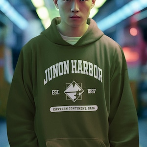 May include: A green hooded sweatshirt with the text "Junon Harbor" in white, a white square with a graphic inside, and the text "Est. 1997 Eastern Continent. Gaia" in white.