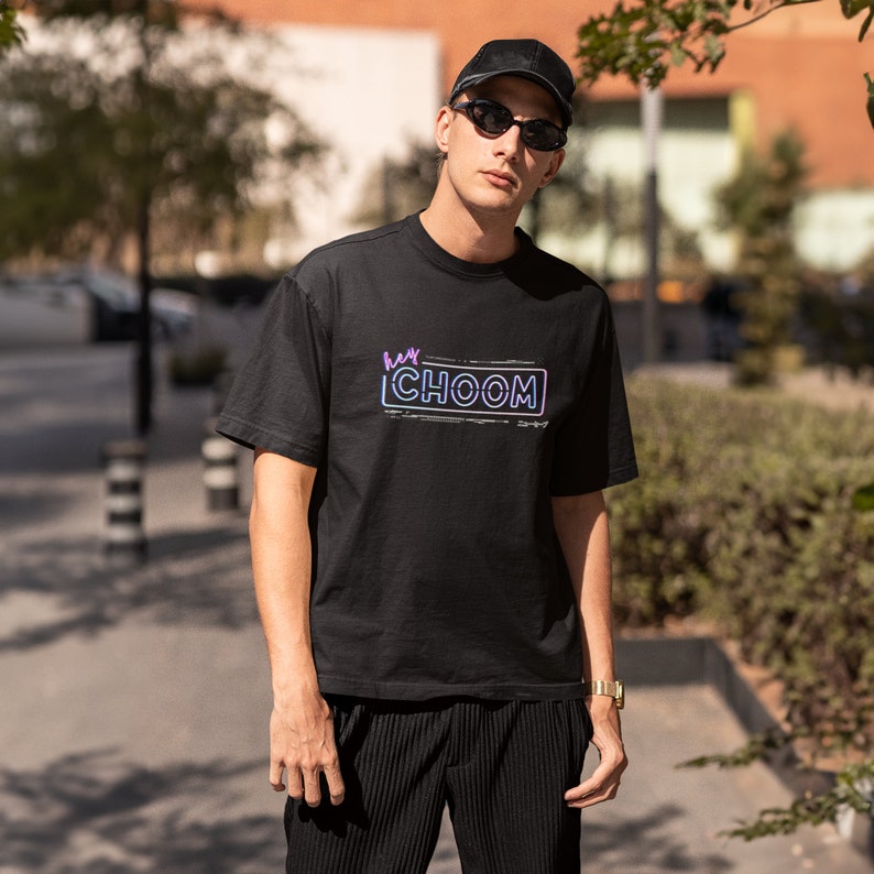 A man outside with a hat and sunglasses wearing a black Cyberpunk 2077 Hey Choom Unisex Oversized T-Shirt by New Save.