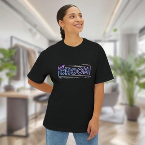 A woman inside of a bedroom wearing a black Cyberpunk 2077 Hey Choom Unisex Oversized T-Shirt by New Save.