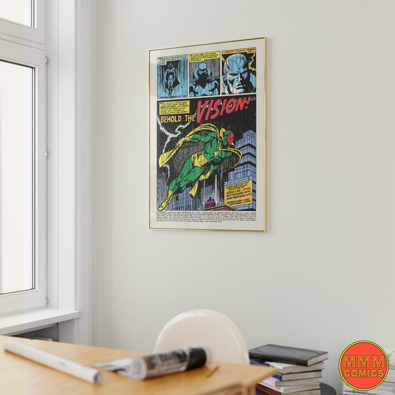 May include: Framed comic book art featuring a green and yellow superhero in flight, with the text "BEHOLD THE VISION!" and "MMM COMICS" logo. The artwork is in a gold frame and hangs on a white wall.