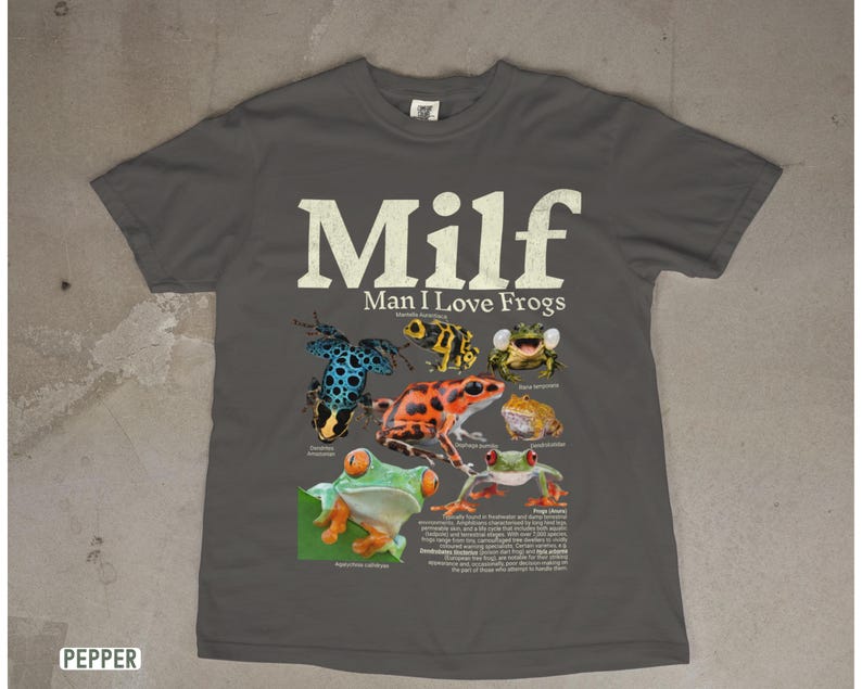 May include: Pepper-colored t-shirt featuring the text "Milf Man I Love Frogs" in white. The shirt displays colorful illustrations of various frog species. A fun and quirky design for frog enthusiasts.