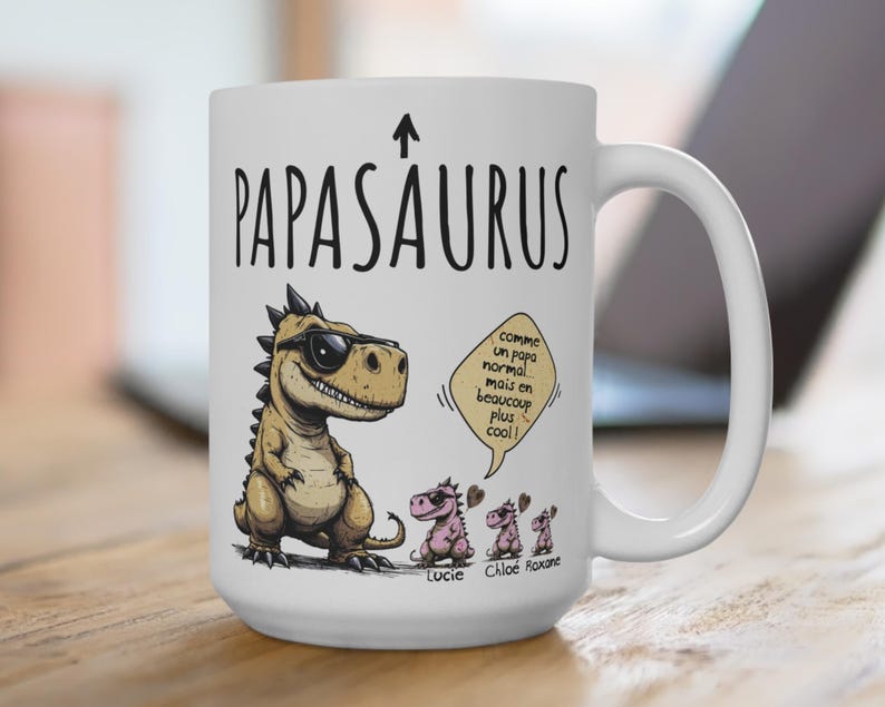 Puede incluir: Taza de cer&aacute;mica blanca con el texto "PAPASAURUS" y una flecha hacia arriba. La taza presenta un dinosaurio de dibujos animados con gafas de sol y tres dinosaurios m&aacute;s peque&ntilde;os. El texto en la taza dice "comme un papa normal mais en beaucoup plus cool!" y los nombres "Lucie, Chlo&eacute;, Roxane."
