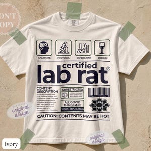 May include: An ivory short-sleeve t-shirt featuring a black graphic print resembling a laboratory label. The design includes icons for calibrate, protocol, experiment, and debrief, with the text certified lab rat and caution contents may be hot.