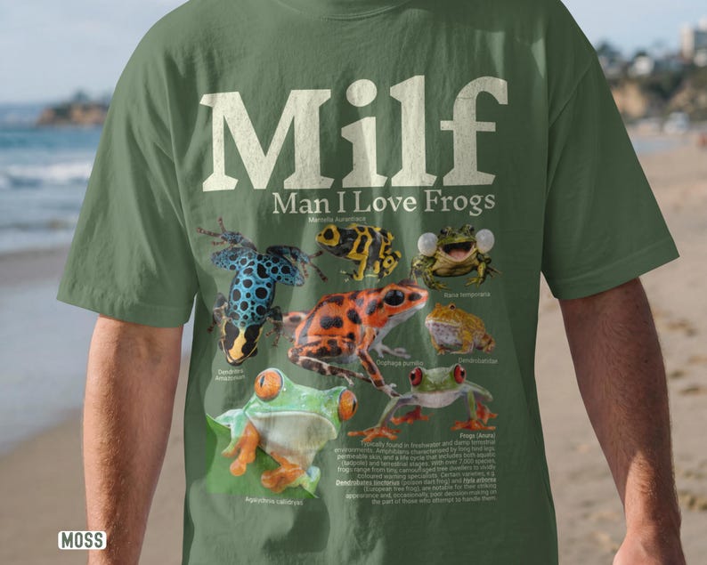 May include: Moss green t-shirt with the text "MILF Man I Love Frogs" in white. The shirt features colorful illustrations of various frog species, including a blue and black frog, and a red and orange frog.