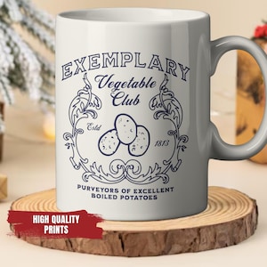Könnte beinhalten: Weißer Keramikbecher mit blauem Design, das den Text "Exemplary Vegetable Club" und Kartoffelillustrationen zeigt. Der Becher steht auf einem Holzuntersetzer. Ein rotes Banner zeigt "High Quality Prints".
