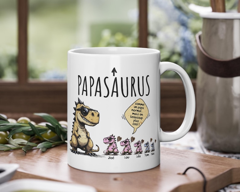 Puede incluir: Taza de cer&aacute;mica blanca con el texto "PAPASAURUS" y un dinosaurio de dibujos animados con gafas de sol. La taza presenta una familia de dinosaurios en rosa y el texto "comme un papa normal mais en beaucoup plus cool!"