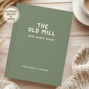 May include: A sage green guest book with the text "THE OLD MILL 2026 GUEST BOOK" in white. The book also includes the text "TROUTBECK, CUMBRIA". A circular sticker on the top left corner reads "CUSTOM FRONT & SPINE".