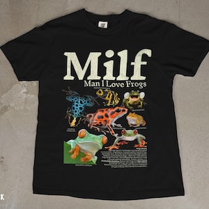 May include: Black t-shirt with the text "Milf Man I Love Frogs" in white. The shirt features a graphic of various colorful frogs with scientific names. The word "BLACK" is printed at the bottom left.