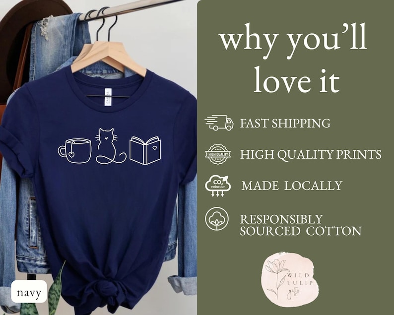 May include: Navy blue t-shirt with a white graphic of a teacup, cat, and book. The text "why you'll love it" is on the right side of the shirt. The shirt is made of responsibly sourced cotton.
