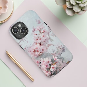 May include: A phone case with a watercolor design of pink cherry blossoms on a light blue background.