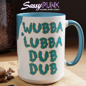 Può includere: Tazza in ceramica bianca con bordo e manico blu turchese. La tazza presenta una grafica con le parole "WUBBA LUBBA DUB DUB" in blu turchese con contorno giallo.