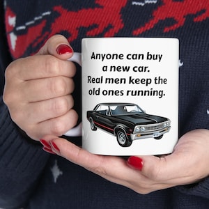 Könnte beinhalten: Eine weiße Keramiktasse mit einer Illustration eines schwarzen und roten Oldtimers und dem Text "Anyone can buy a new car. Real men keep the old ones running."