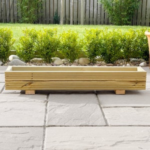 May include: A rectangular wooden planter box with a natural wood finish. The planter is sitting on a grey patio.